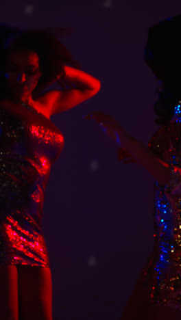 Vertikales-Video-Von-Zwei-Frauen-In-Einer-Nachtclubbar-Oder-Disco,-Die-Mit-Funkelnden-Lichtern-Im-Hintergrund-Tanzen
